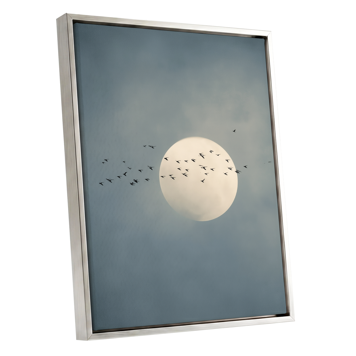 Framed wall art featuring a pale full moon against a muted blue-gray cloudy sky, with small black bird silhouettes flying around it. The artwork is shown in a slim metallic frame on a plain white background.