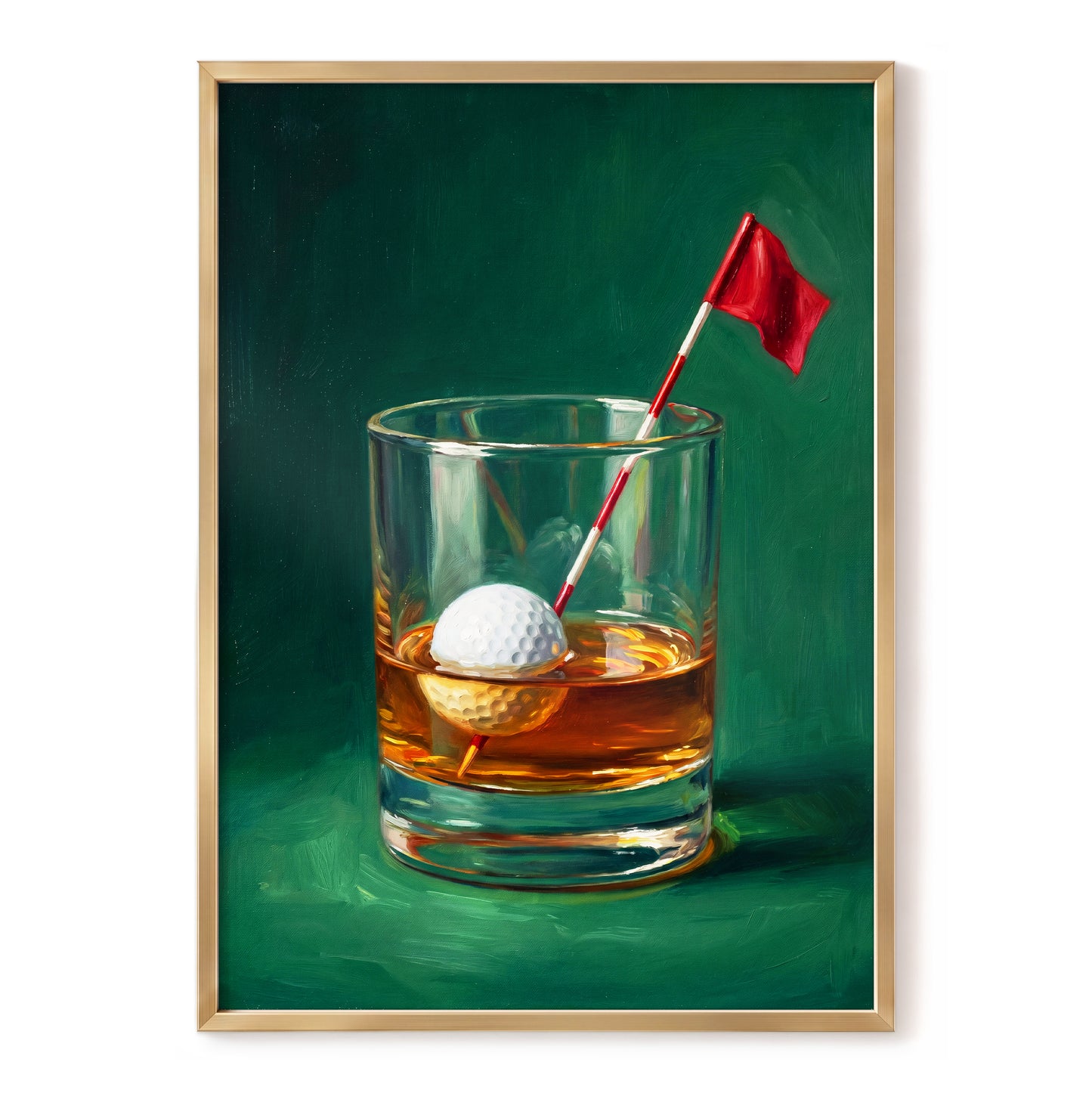 A framed art print depicting a still life of a whiskey glass with an amber drink, a white golf ball, and a small red flag on a dark green background, shown against a white wall.