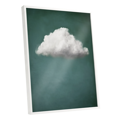 A vertical framed wall art print showing a single white cloud against a dark teal-green sky with soft light rays, photographed at an angle with a white frame on a light gray background.