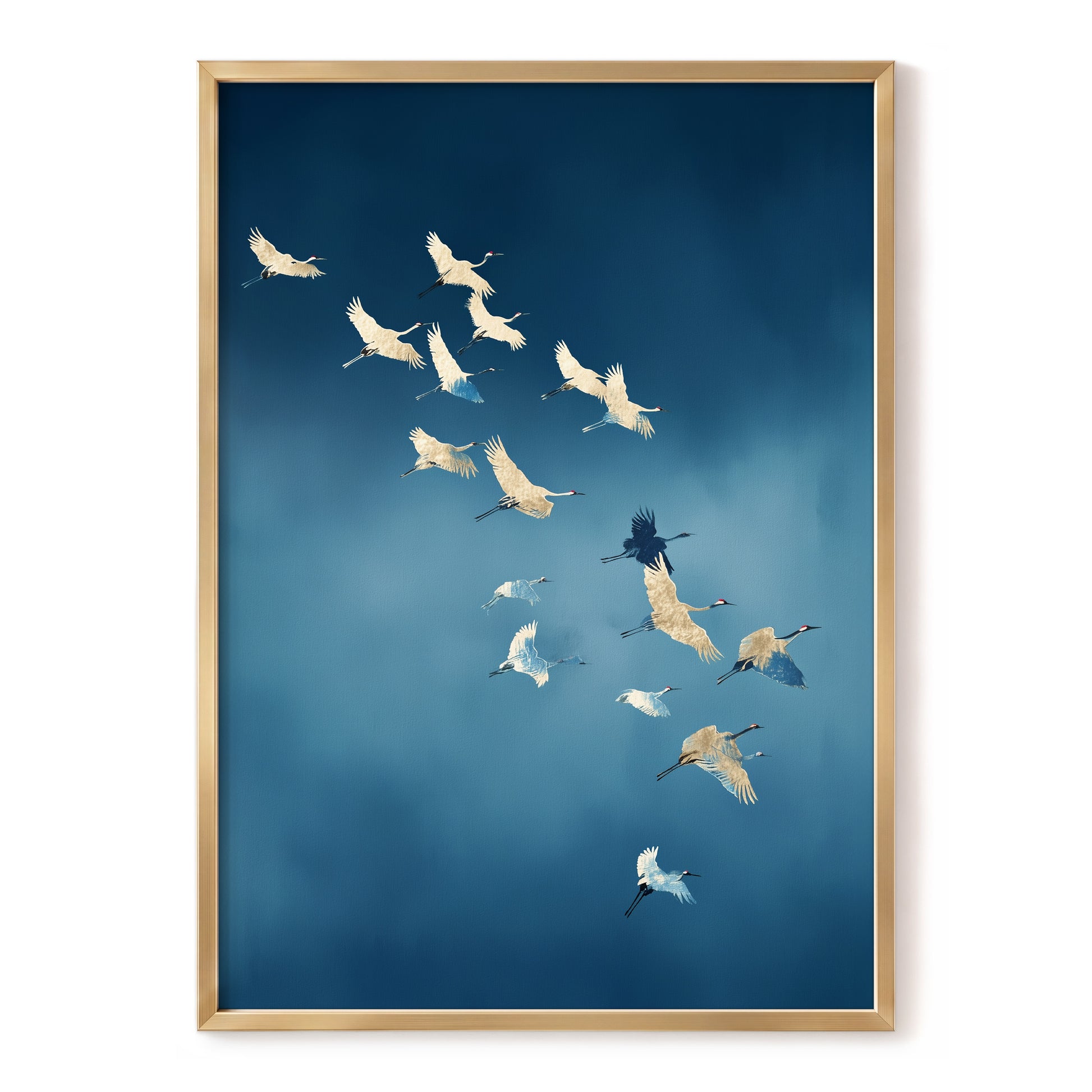 Framed wall art featuring a flock of white cranes flying across a deep blue sky, presented in a light wood frame against a white background.