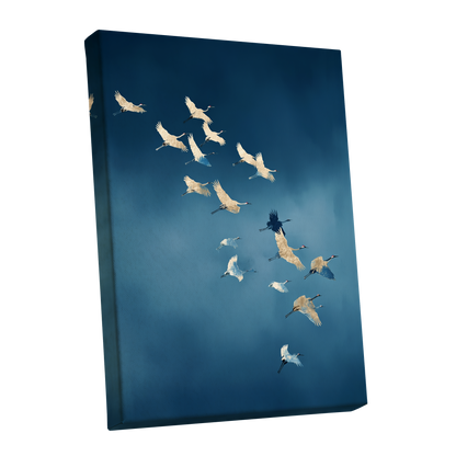 A vertical canvas wall art print showing a flock of cranes flying across a deep blue sky, photographed at an angle against a plain white background.