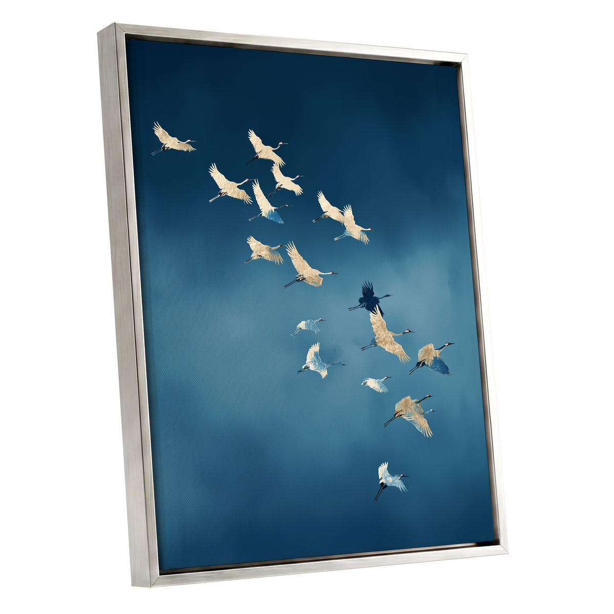 A framed wall art print showing a flock of cranes flying across a deep blue sky, presented at an angle with a silver frame on a white background.