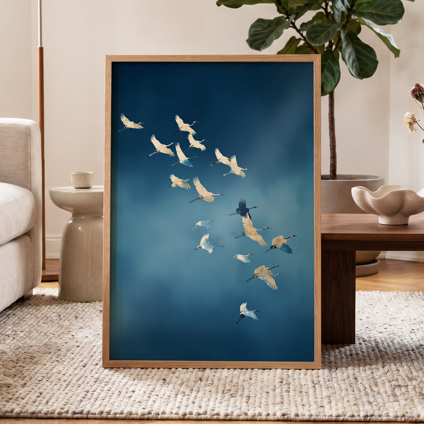 A framed art print featuring a flock of white and blue cranes flying against a deep blue background, styled in a modern living room setting.