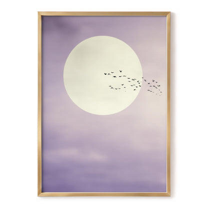 A framed art print featuring a large cream-colored moon and a flock of small black birds against a soft lavender-purple sky, enclosed in a thin gold frame.