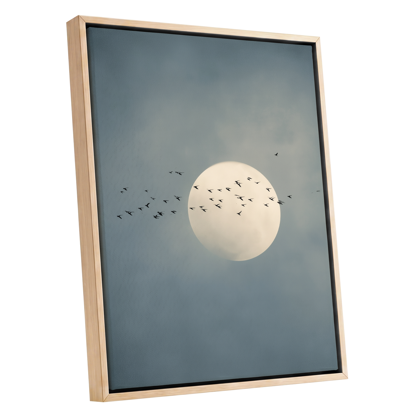 Framed wall art featuring a pale full moon centered against a muted blue-gray cloudy sky, with small black bird silhouettes flying around it. The artwork is shown in a light natural wood frame on a plain white background.