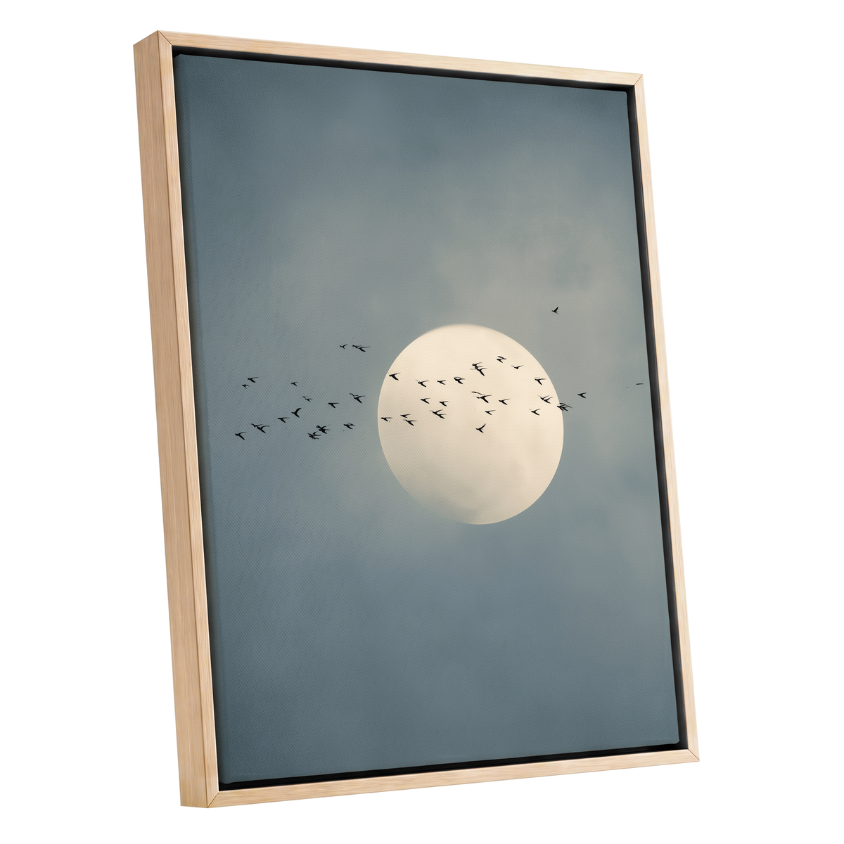 Framed wall art featuring a pale full moon centered against a muted blue-gray cloudy sky, with small black bird silhouettes flying around it. The artwork is shown in a light natural wood frame on a plain white background.