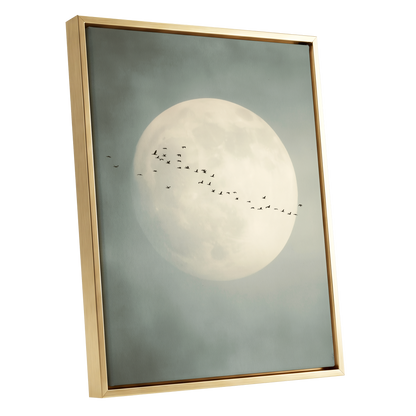 Framed wall art featuring a large pale moon in a misty gray-blue sky with a small flock of birds flying across it, shown in a gold frame on a white background.