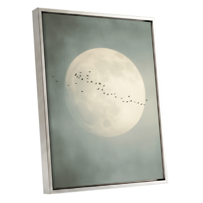 Framed wall art featuring a large pale moon in a misty gray-blue sky with a small flock of birds flying across it, shown in a gold frame on a white background.