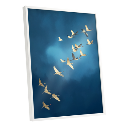 A framed wall art print showing a flock of cranes flying across a deep blue sky, displayed at an angle with a white frame against a clean white background.