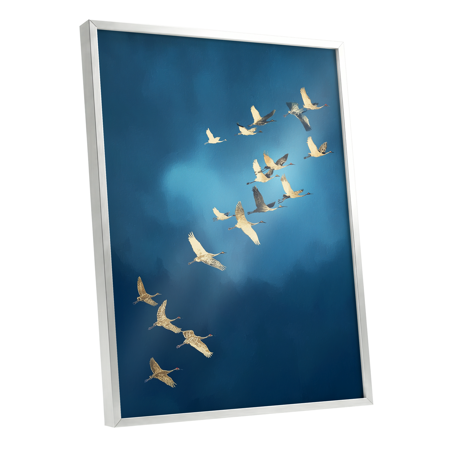 Framed wall art featuring a flock of white cranes flying across a deep blue sky, shown in a silver frame at an angle.