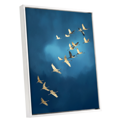 A framed wall art print showing a flock of cranes flying across a deep blue sky, presented at an angle against a plain white background.