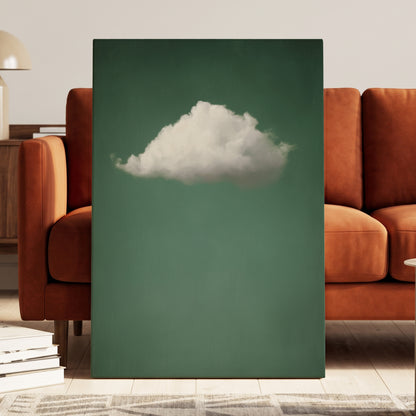 A vertical canvas wall art print featuring a white cloud against a muted teal-green background, styled leaning against a rust-orange sofa in a modern living room setting.