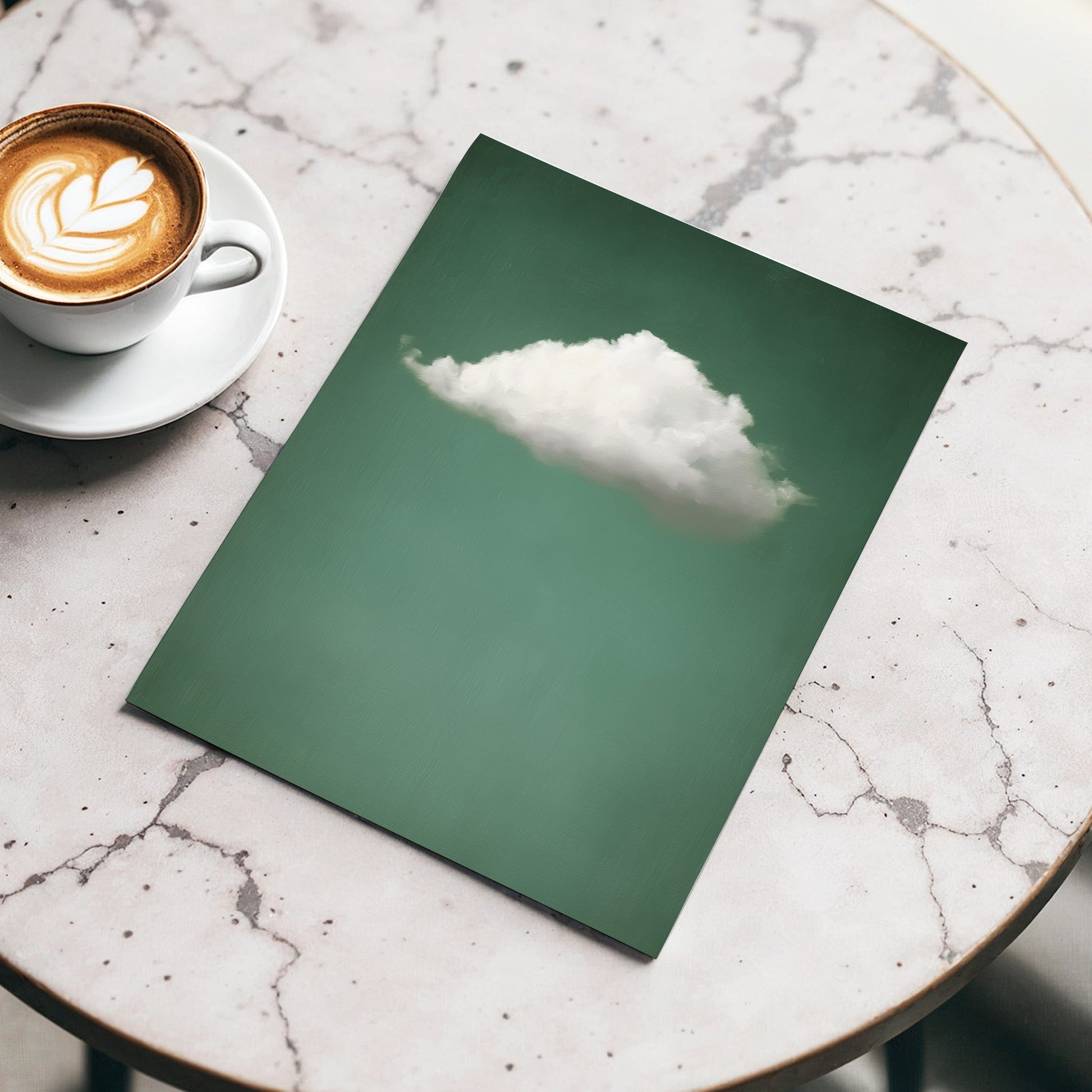Green notebook with a cloud illustration on a marble surface next to a cup of coffee.
