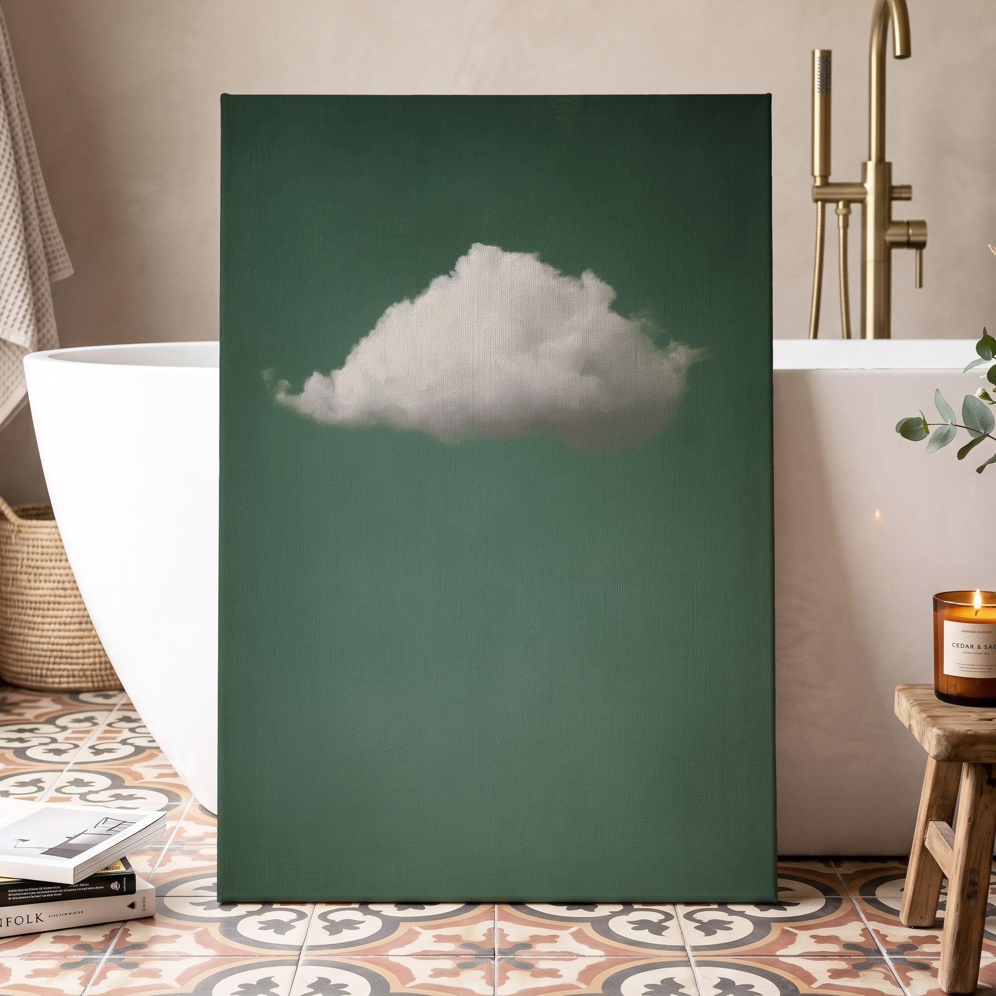 A vertical canvas wall art print featuring a single fluffy white cloud against a deep teal-green background, styled in a modern bathroom setting next to a white freestanding bathtub.