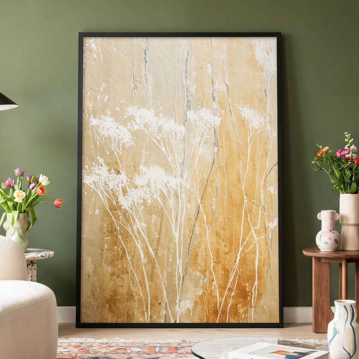 Golden Meadow Texture: a large framed abstract canvas print featuring white textured brushstrokes over a warm beige and gold background, displayed in a black frame on a dark green wall in a styled living room setting.