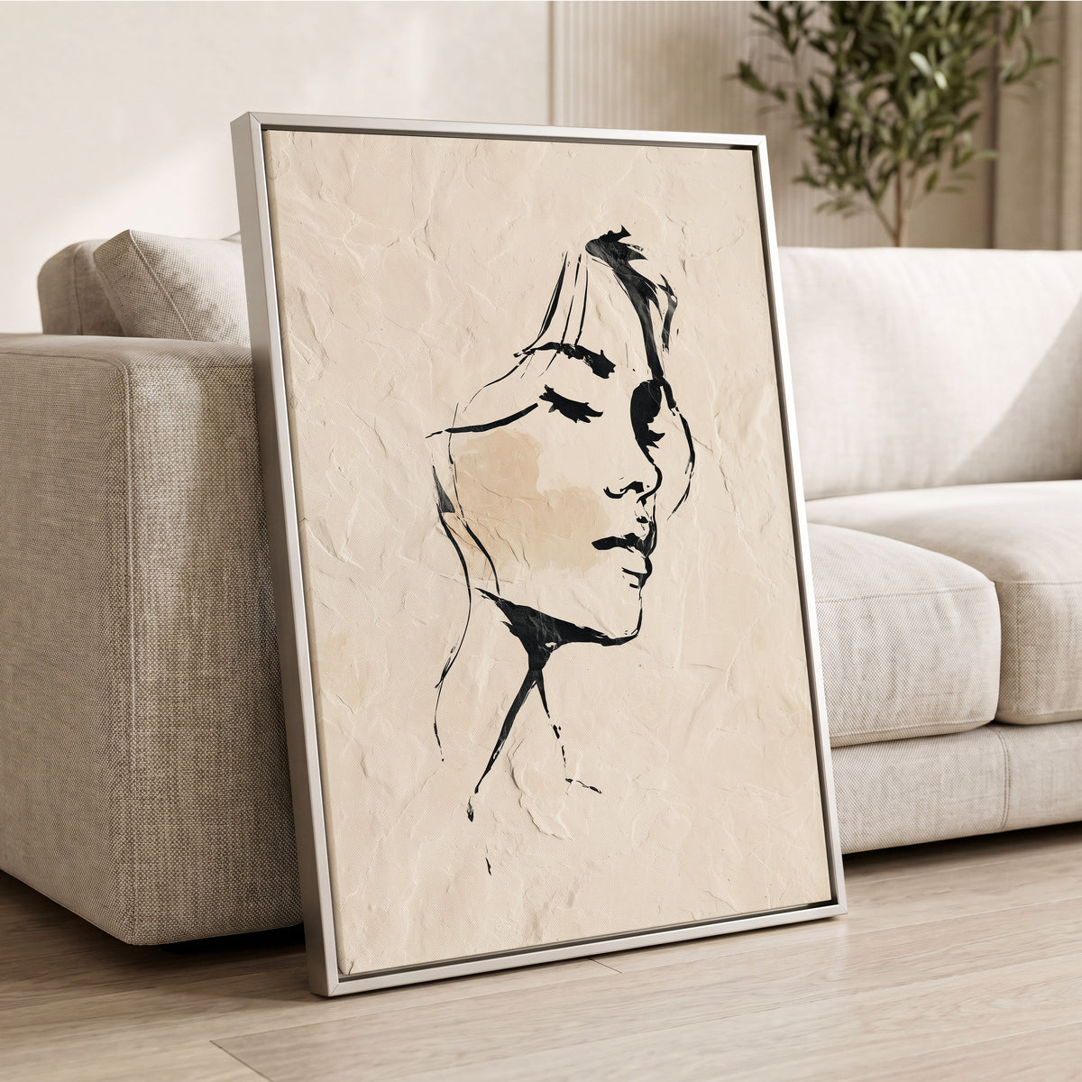 Minimal Woman Portrait: a framed art print featuring a minimalist black ink sketch of a woman's face on a textured beige background, leaning against a light beige sofa in a modern living room setting.