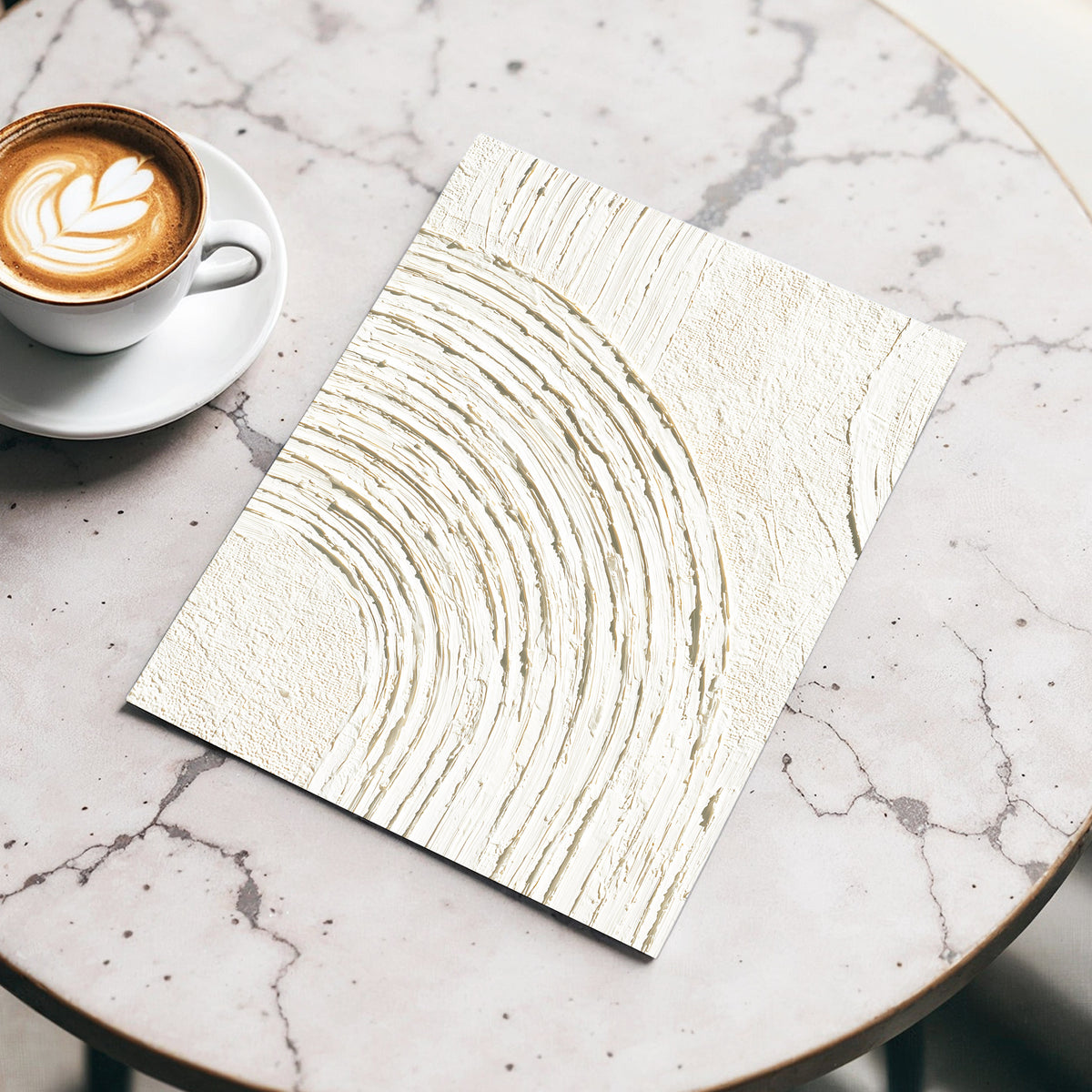Soft Ivory Arch Texture: a square art print with a textured cream and gold abstract wavy pattern, displayed on a light marble table next to a cup of latte.